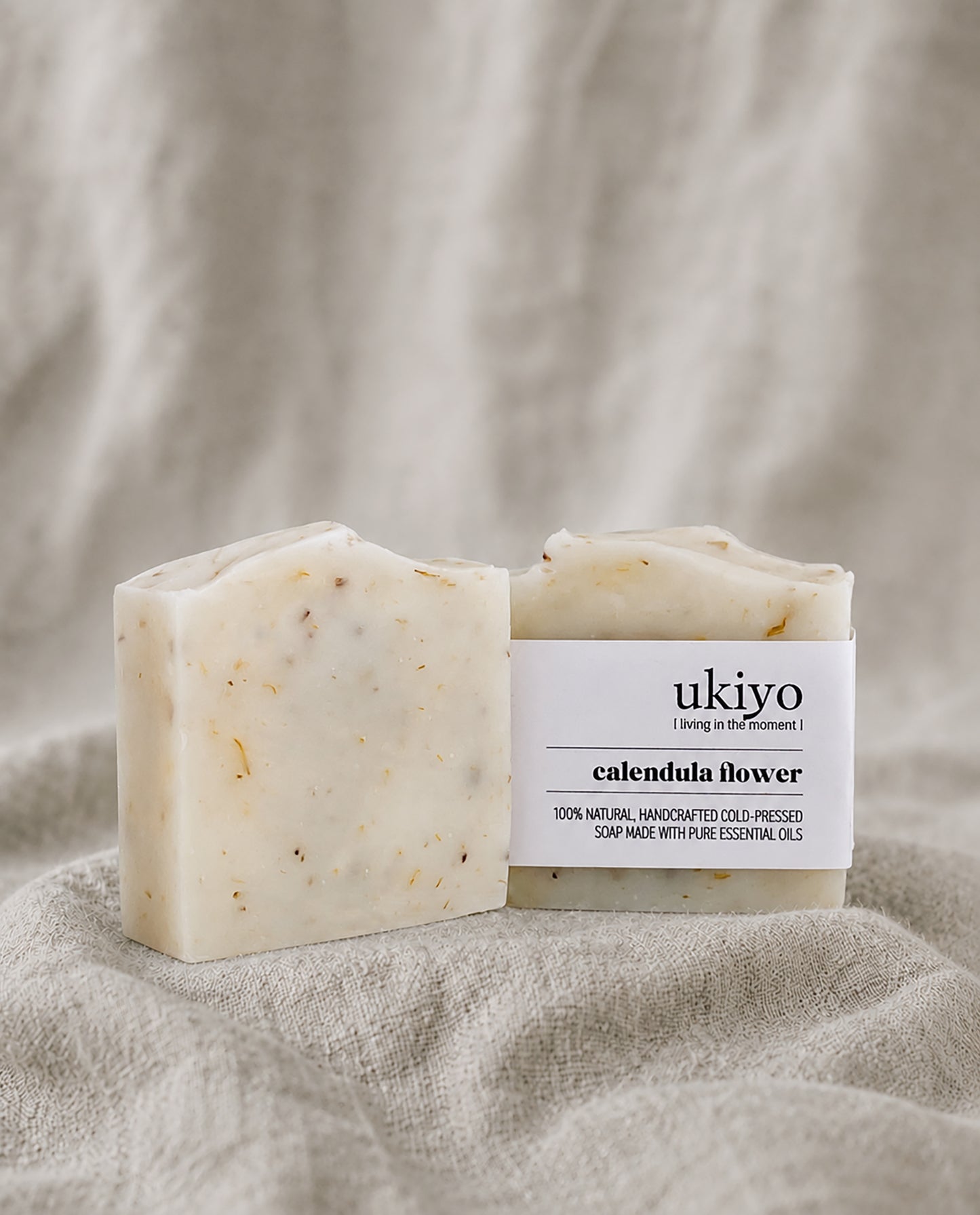 Bar of calendula soap with packaging labeled 'ukiyo' on a textured beige background