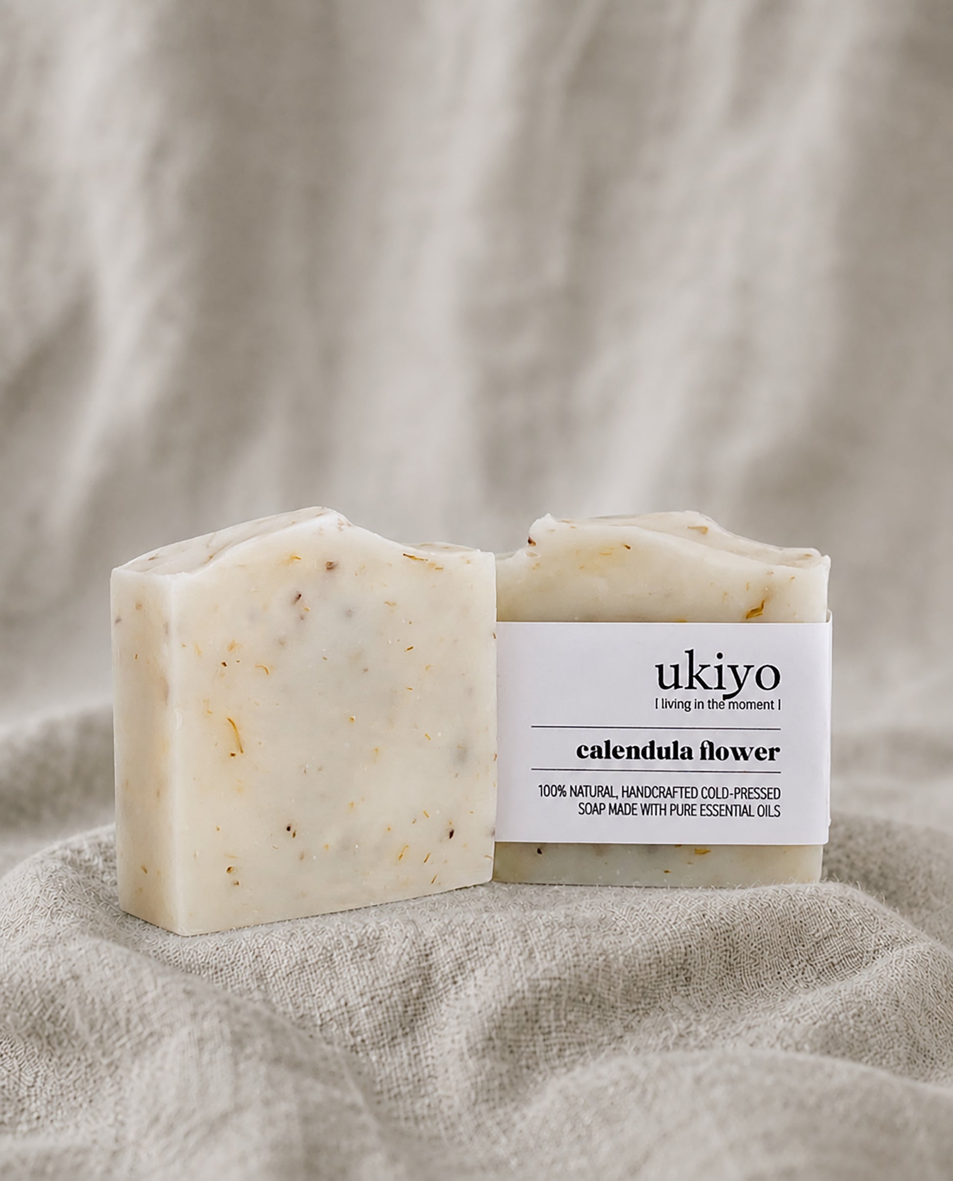 Bar of calendula soap with packaging labeled 'ukiyo' on a textured beige background