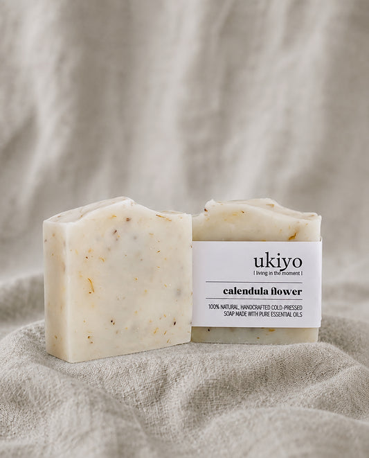 Bar of calendula soap with packaging labeled 'ukiyo' on a textured beige background