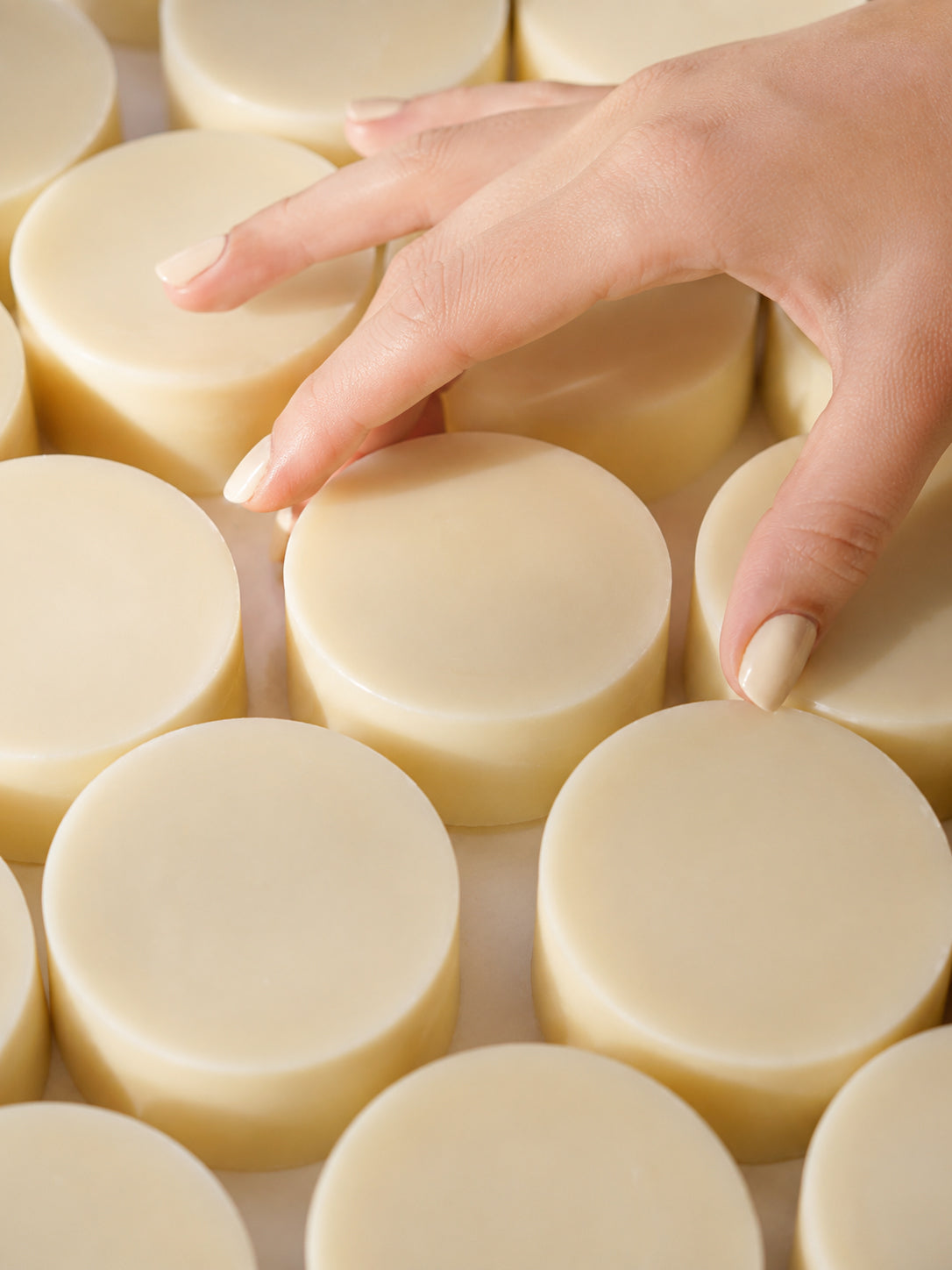 Hand touching a stack of round conditioner  bars.